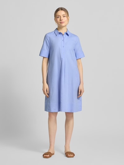Modelka kobieca nosi Knielanges Hemdblusenkleid aus reiner Baumwolle od Milano Italy, niebieska, luźny krój, krótki rękaw, długość do kolan, czysta bawełna, kołnierzyk z guzikami, szerokość w rozmiarze 36: 52 cm, długość tyłu: 94 cm, długość rękawa: 28 cm, widok całej sylwetki z przodu.