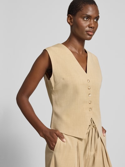 Modelka kobieca ma na sobie kamizelkę Slim Fit Weste mit Viskose-Anteil Modell 'DYLAN' od SUNCOO PARIS, beżowy kolor, mieszanka materiałów z dodatkiem wiskozy, dekolt w serek, listwa guzikowa, Szerokość ramion w rozmiarze S: 38 cm, szerokość klatki piersiowej w rozmiarze S: 52 cm, długość tyłu: 43 cm, ujęcie górnej części ciała z przodu.