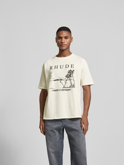 Männermodel trägt Regular Fit T-Shirt mit Logo-Print von RHUDE in Creme mit schwarzem Motiv-Print, Rundhalsausschnitt, Ganzkörperansicht von vorne