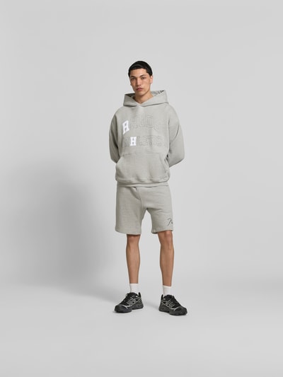 Männermodel trägt Sweatshorts aus Baumwoll-Mix von RHUDE in Gerade Passform, elastischer Bund mit Tunnelzug, Label-Stitching, Eingrifftaschen, Ganzkörperansicht von vorne.