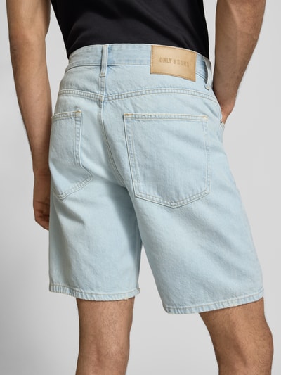 Männermodel trägt Regular Fit Jeansshorts aus reiner Baumwolle Modell 'EDGE' von Only & Sons in hellblauem Denim mit Label Patch, Ganzkörperansicht Rückansicht.