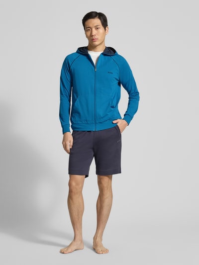 Männermodel trägt Regular Fit Sweatjacke aus Baumwoll-Mix von BOSS, Optik: Unifarben, Passform: Regular-Fit, Reißverschluss, Label-Stitching-Applikation, Kontraststreifen, Kapuze, Langarm, Ärmelabschluss: Gerippt, Rumpfabschluss: Gerippt, Taschen: Kängurutasche, Materialverarbeitung: Sweat, Material: Baumwoll-Mix, Ganzkörperansicht von vorne.