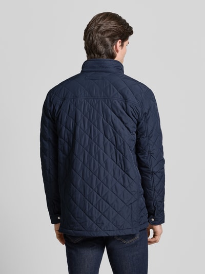 Männermodel trägt dunkelblaue Regular Fit Steppjacke mit Logo-Stitching Modell 'Windcheater' von Gant, Stepp-Optik, Ganzkörperansicht Rückansicht.