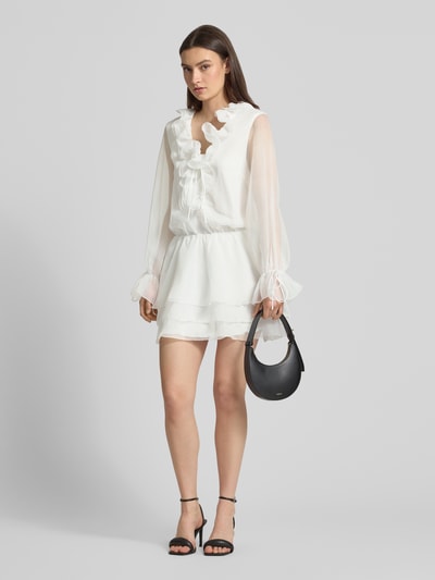 Frauenmodel trägt Minikleid mit Rüschen und Schnürung von Gina Tricot, semitransparent, A-Linie, Weiß, Ganzkörperansicht von vorne. Rückenlänge 86 cm, Brustweite 48 cm, Ärmellänge 85 cm, Größe S.