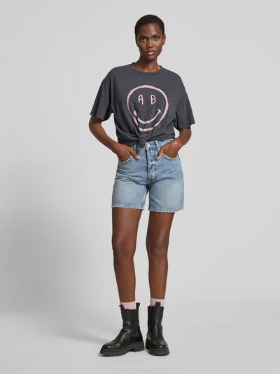 Frauenmodel trägt Relaxed Fit T-Shirt mit Logo-Print von Anine Bing aus reiner Baumwolle, dunkles Grau, Rundhalsausschnitt, kurzärmelig, Rückenlänge 60 cm, Ganzkörperansicht von vorne.