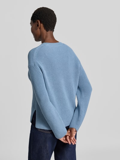 Männermodel trägt Loose Fit Pullover aus reiner Baumwolle von Marc O'Polo in hellblau mit grober Strickstruktur, Ganzkörperansicht Rückansicht.