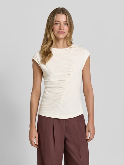 Vrouwenmodel draagt T-shirt met ronde hals en draperingen van Christian Berg Woman, mix van katoen en micromodal, slim fit, kapmouwen, ruglengte maat S 56 cm, crème met asymmetrische plooien, vooraanzicht volledige lichaamsopname