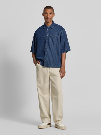 Mężski model nosi Oversized Jeanshemd aus Baumwoll-Lyocell-Mix od Armedangels, dżinsowa faktura, kent kołnierz, krój oversize, twill, widok całej sylwetki z przodu.