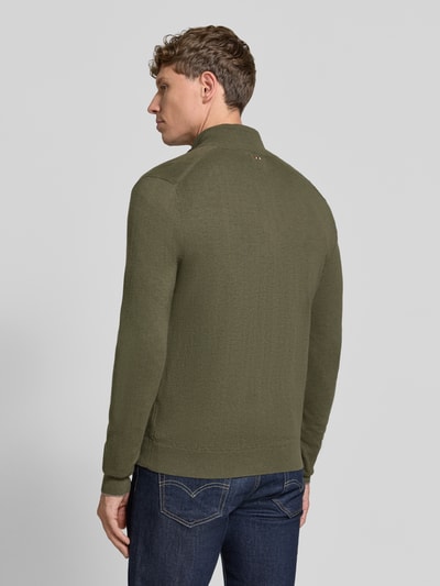 Männermodel trägt Strickjacke mit Logo-Stitching Modell 'DAMAVAND' von Napapijri in Oliv, reine Wolle, Rückansicht, Ganzkörperansicht.