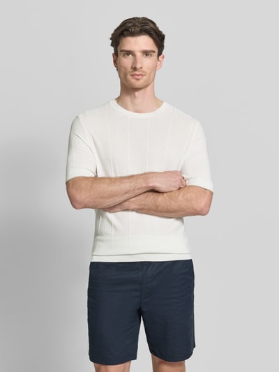 Männermodel trägt Strickshirt mit Viskose-Anteil Modell 'Gion' von CINQUE, Viskose-Mix, Gerader-Schnitt, Rundhalsausschnitt, Halbarm, marineblaue Shorts, gerippte-Abschlüsse, Rückenlänge bei Größe M 71 cm, Ganzkörperansicht von vorne.