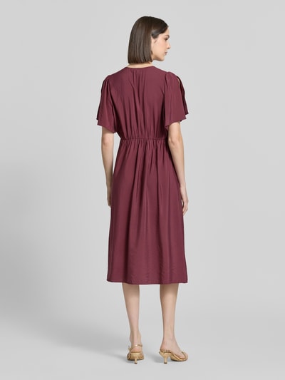 Frauenmodel trägt Midikleid aus Viskose-Mix mit V-Ausschnitt Modell 'Aniva' von ICHI, tailliert, knielang, dunkelrot, Ganzkörperansicht Rückansicht.
