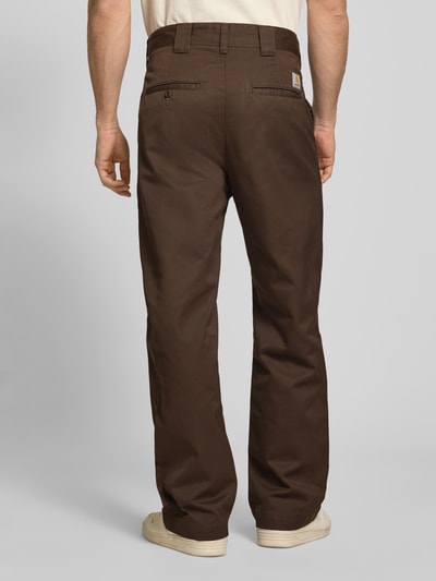 Männermodel trägt braune Hose mit Gesäßtaschen Modell 'Denison' von Carhartt Work In Progress aus Material-Mix, Relaxed-Fit, Bundweite 46 cm, Innenbeinlänge 75 cm, Ganzkörperansicht Rückansicht.