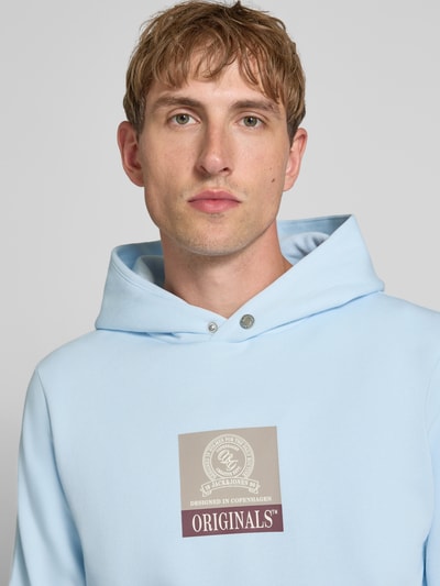 Männermodel trägt Hoodie mit Label-Print Modell 'FREDERIKSBERG' von JACK & JONES, hellblauer Baumwoll-Mix, Nahaufnahme Oberkörper.