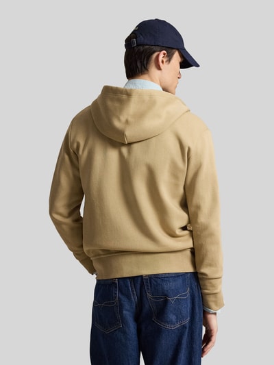 Męski model nosi Regular Fit Sweatjacke aus Baumwoll-Mix von Polo Ralph Lauren w kolorze beżowym, proste formy, tekstura gładka, widok całej sylwetki od tyłu.