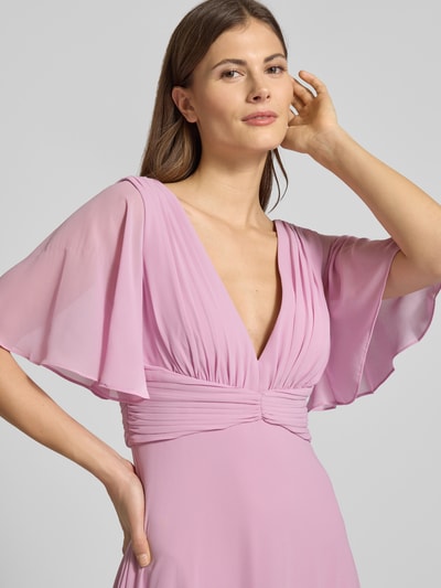 Kobiece modelka nosi Sukienka wieczorowa Regular Fit Abendkleid mit V-Ausschnitt von Jake*s Cocktail, szyfon, dekolt w serek, krój regular fit, rękaw o dł. 1/2, efekt plisowania, dekolt na plecach, wszyty zamek błyskawiczny, halka pod spódnicę, jasnoróżowa, gładka tekstura, z przodu, zbliżenie na górną część ciała