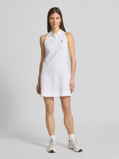 Frauenmodel trägt Slim Fit Polokleid aus Baumwoll-Mix von Lacoste Sport in Weiß mit Logo-Detail und kurzem Kragen, Ganzkörperansicht von vorne.