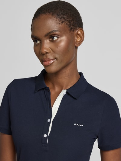 Frauenmodel trägt Knielanges Polokleid mit Label-Stitching von Gant in Dunkelblau, Baumwoll-Elasthan-Mix, Nahaufnahme Oberkörper.