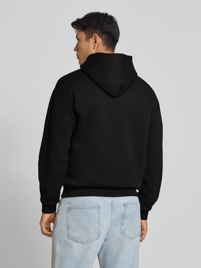 Männermodel trägt Relaxed Fit Sweatshirt aus Baumwoll-Mix mit Känguru-Tasche von REVIEW, schwarze Farbe, Rückenansicht, Ganzkörperansicht Rückansicht.