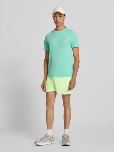 Männermodel trägt Shorts mit elastischem Bund und Logo von New Balance, Regular-Fit, helle Farben, Ganzkörperansicht von vorne.