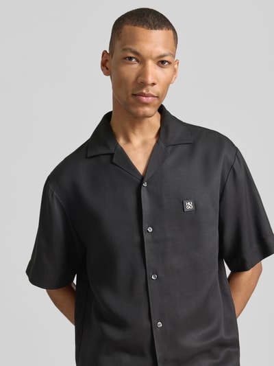 Männermodel trägt Relaxed Fit Freizeithemd aus reinem Lyocell Modell 'ESPINO' von HUGO in Schwarz, unifarben, Nahaufnahme Oberkörper.