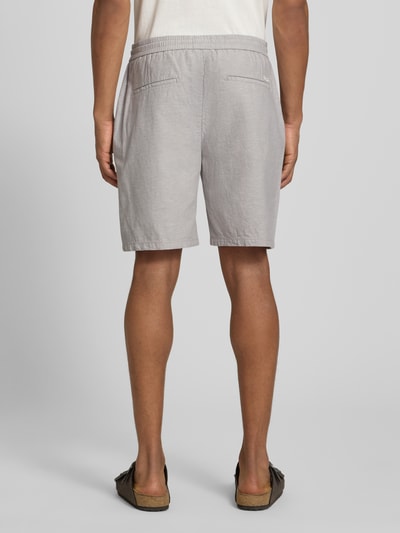 Männermodel trägt Shorts mit elastischem Bund von Scotch & Soda, Baumwoll-Leinen-Mix, hellgrau, strukturierte Oberfläche, Ganzkörperansicht Rückansicht.