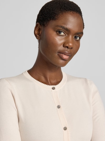 Vrouwenmodel draagt Regular Fit gebreid jack uit Viscosemix met geschulpte zoom van Christian Berg Woman, knoopsluiting, lange mouw, ribboorden, ruglengte maat S 56 cm, mouwlengte maat S 61 cm, Nahaufnahme bovenlichaam.