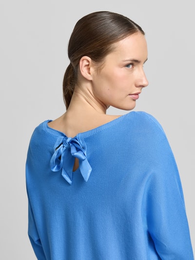 Frauenmodel trägt Relaxed Fit Pullover aus Viskose-Mix in Strick-Optik von comma, leuchtend blau, Satinbanddetail, Nahaufnahme Rückansicht. Damen Pullover, U-Boot-Ausschnitt, 3/4-Arm, elastische Abschlüsse, Rückenlänge 47 cm, Ärmellänge 45 cm.