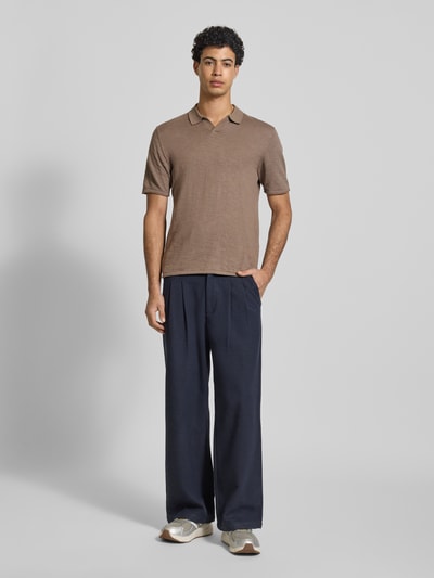 Männermodel trägt Slim Fit Poloshirt in Strick-Optik Modell 'Kane' von JACK & JONES aus reiner Baumwolle, Ganzkörperansicht von vorne.