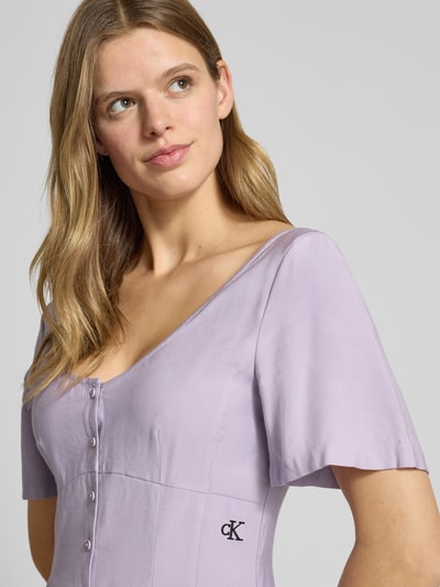 Modelka kobieca nosi Sukienka mini z wyhaftowanym logo od Calvin Klein Jeans, mieszanka wiskozy, luźny krój, listwa guzikowa, dekolt w łódkę, jednokolorowy, szerokość w rozmiarze S: 44 cm, długość tyłu w rozmiarze S: 68 cm, długość rękawów w rozmiarze S: 26 cm, zbliżenie górnej części ciała.