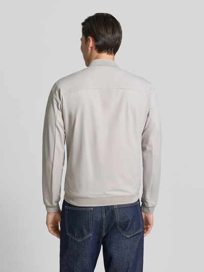 Männermodel trägt Regular Fit Jacke mit Stehkragen Modell 'Campo' von SCANDINAVIAN EDITION in Hellgrau, glatte Textur, Ganzkörperansicht Rückansicht. Rückenlänge bei Größe M: 67 cm, Schulterbreite: 44 cm, Brustweite: 51 cm, Ärmellänge: 64 cm, Zweiwege-Reißverschluss, Eingrifftaschen mit Reißverschluss, elastische Abschlüsse.