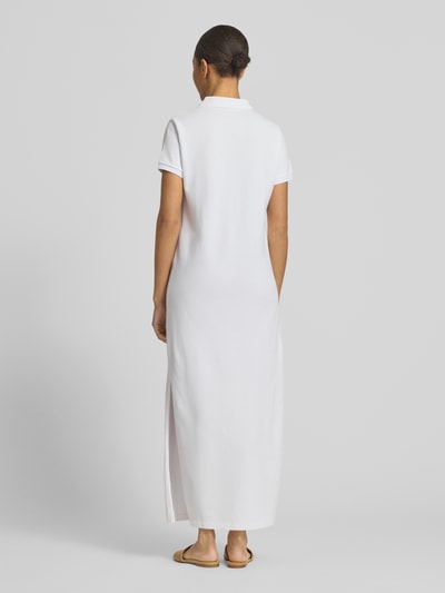 Modelka nosi Straight Fit Polokleid aus reiner Baumwolle od Polo Ralph Lauren, biała, jednolita, bawełna pique, midi, krótki rękaw, logo, rozcięcia po bokach, widok całej sylwetki z tyłu.