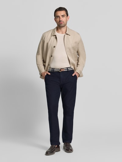Männermodel trägt Chino mit Gürtel und Eingrifftaschen Modell 'WARREN' von Scotch & Soda, Baumwoll-Mix, Straight Fit, Ganzkörperansicht von vorne.