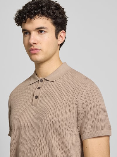 Męski model nosi Modern Fit Poloshirt mit kurzer Knopfleiste Modell 'JESS' od Jack & Jones, bawełniany miks, półprzezroczysty design, beżowy kolor, strukturalna tekstura, polokołnierzyk, krótka plisowana listwa guzikowa, kontekst: długość tyłu w rozmiarze M: 68 cm, półzbliżenie przód.