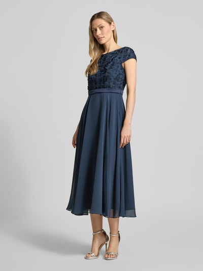 Kobiece modelka nosi Cocktailkleid mit Stitchings und Perlen von Christian Berg Cocktail, mieszanka materiałów z dodatkiem streczu, linia a, sukienka midi, hafty, perły, okrągły dekolt, długość tyłu w rozmiarze 36: 124 cm, szerokość w rozmiarze 36: 45 cm, granatowy, gładka tekstura spódnicy, połyskliwe detale, widok całej sylwetki z przodu.