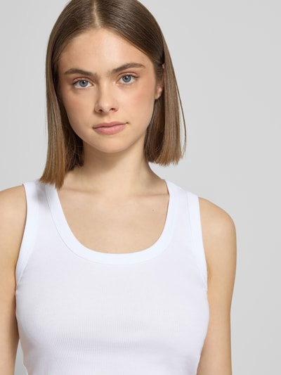 Vrouwenmodel draagt Slim Fit Tank Top aus Baumwoll-Mix Modell 'EASY' van Only in effen wit, fijne ribstructuur, brede bandjes, u-hals, katoenmengsel. Close-up bovenlichaam.