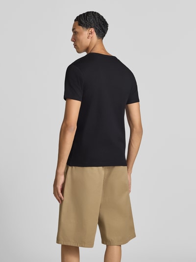Męski model nosi Regular Fit T-Shirt aus Baumwoll-Mix od JACK & JONES, kolor czarny, gładka faktura, długość tyłu w rozmiarze M: 67 cm, krój regular fit, okrągły dekolt, z krótkim rękawem, ganzkörperansicht rückansicht
