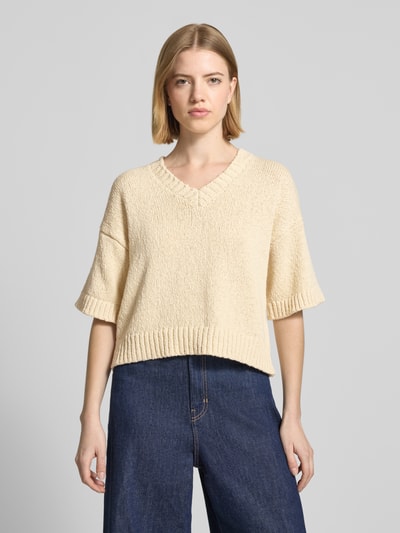 Frauenmodel trägt Regular Fit Pullover in Strick-Optik Modell 'Hannalie' von MSCH Copenhagen aus Reine Baumwolle, Halbarm, V-Ausschnitt, beige Farbe, strukturierte Oberfläche, Ganzkörperansicht von vorne.