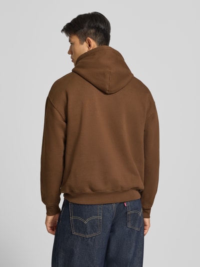 Männermodel trägt Regular Fit Hoodie aus Baumwoll-Mix von Levi's® in Braun, schlichte Optik, weiche Textur, Ganzkörperansicht Rückansicht.