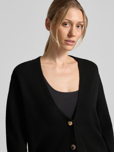 Frauenmodel trägt Relaxed Fit Cardigan aus reiner Wolle Modell 'Maglia Aperta' von Liu Jo White, Strick-Optik, Schwarz, Nahaufnahme Oberkörper.