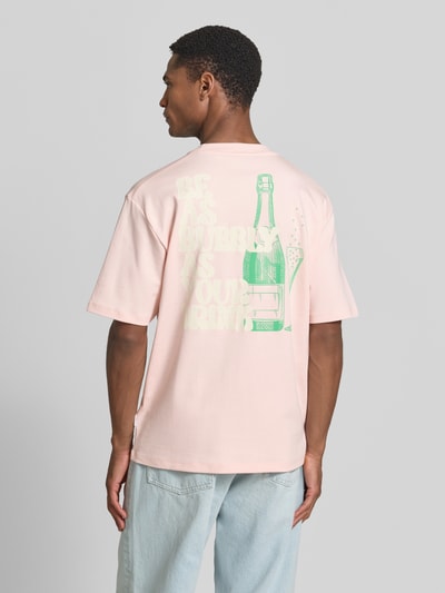 Männermodel trägt Oversized T-Shirt mit Label-Print von Lindbergh in Hellrosa aus Reine Baumwolle, Rückenlänge bei Größe M 70 cm, Ganzkörperansicht Rückansicht.
