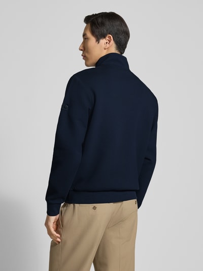 Męski model nosi Regular Fit Jacke mit Stehkragen Modell 'Scott' od Peuterey, granatowy kolor, kieszenie, elastyczne wykończenia, widok całej sylwetki z tyłu. Krój regular fit, długość tyłu 66 cm, długość rękawa 66 cm, elastyczny materiał z bawełną.
