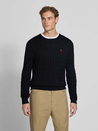 Männermodel trägt Regular Fit Pullover aus reiner Baumwolle von Polo Ralph Lauren in Schwarz, Struktur mit Zopfmuster, Ganzkörperansicht von vorne. Herren Pullover von Polo Ralph Lauren.
