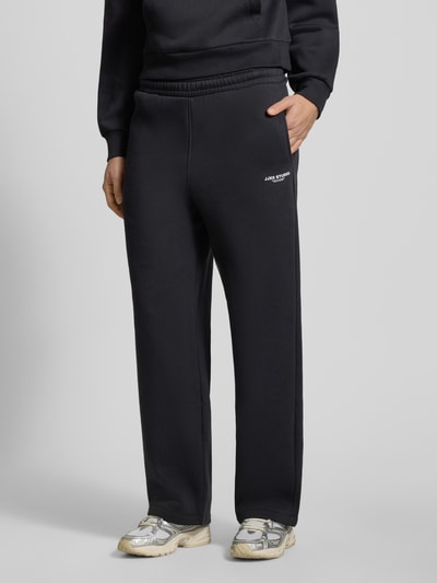Męskimodel nosi High Waist Sweatpants mit elastischem Bund und Logo od JJXX, czarne, szerokie nogawki, mieszanka bawełny, widoczne logo, długość wewnętrzna nogawki 74 cm, widok z przodu, ujęcie do połowy ciała.