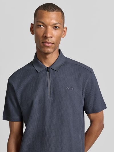 Mannelijk model draagt donkerblauw regular fit poloshirt uit pure katoen model 'Pe_RibNylon' van BOSS Orange, Nahaufnahme Oberkörper.