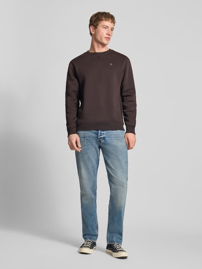 Männermodel trägt Slim Tapered Fit Jeans mit Eingrifftaschen Modell 'Streem' von G-Star Raw aus reiner Baumwolle in Hellblau, Ganzkörperansicht von vorne. Bundweite bei Größe 32/32: 44 cm, Innenbeinlänge: 80 cm.