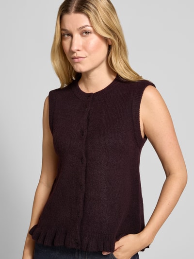 Frauenmodel trägt Strickweste mit Rundhalsausschnitt Modell 'Frilana' von mbyM, dunkles Lila, Knopfleiste, Material-Mix mit Woll-Anteil, Ganzkörperansicht von vorne, Regular Fit, Rückenlänge bei Größe S 50 cm.