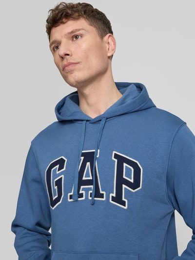 Mannelijk model draagt Hoodie met Kängurutasche van GAP, blauw katoenmix met label-stitching, losse fit, detailopname bovenlichaam.