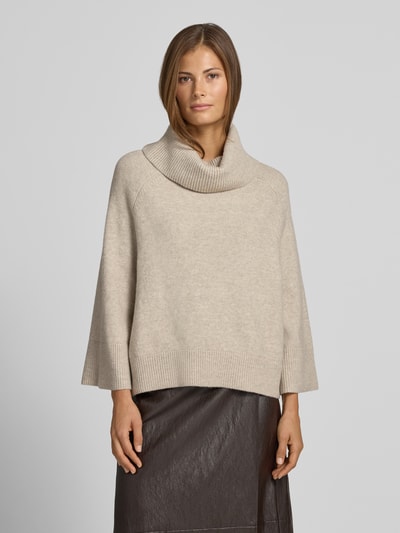 Frauenmodel trägt Rollkragenpullover mit Raglanärmeln von COMMA in Beige, lockerer Schnitt, gerippte Abschlüsse, Ganzkörperansicht von vorne. Elastischer Material-Mix mit Lanawoll-Anteil, Rückenlänge 54 cm, Ärmellänge 50 cm.