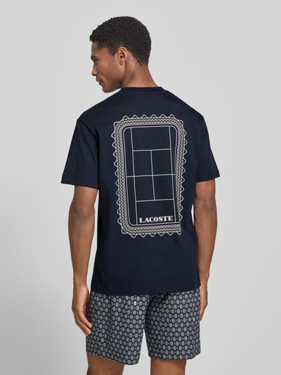 Männermodel trägt dunkelblaues Regular Fit T-Shirt aus reiner Baumwolle Modell 'CN Tenniscourt Backprint' von Lacoste, Herren T-Shirt, geometrischer weißer Print, Ganzkörperansicht Rückansicht.