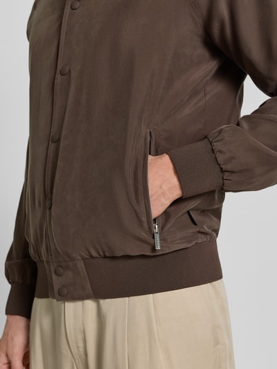 Männermodel trägt Blouson aus Seide mit Reißverschlusstaschen van bugatti in bruin, regular fit, knoopsluiting, detailopname zijaanzicht.